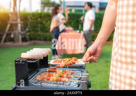 Un homme asiatique cuisine barbecue grill et saucisse pour un groupe d'amis à manger la fête dans le jardin à la maison. Groupe d'amis ayant jardin extérieur barbecue la Banque D'Images
