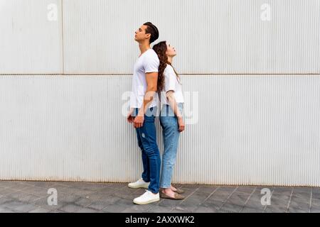 Portrait de malheureux frustrés couple standing back to back pas la parole aux autres après une dispute en étant debout sur fond gris. E négative Banque D'Images