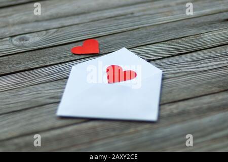 Message d'amour - deux coeurs de papier rouge et enveloppe sur un fond gris en bois Banque D'Images