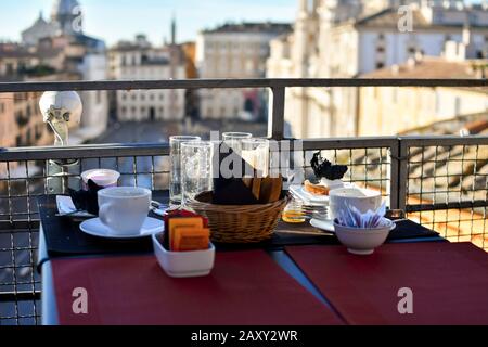 Les restes d'un petit déjeuner continental sur un bar sur le toit surplombant la Piazza Navona en début d'été à Rome, en Italie. Banque D'Images