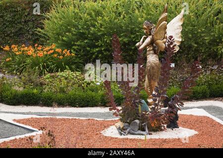 Statue d'une fée mythique à ailes d'or sur un parterre en forme d'étoile dans le jardin de fées en été à la route des Gerbes d'Angelica jardin en été. Banque D'Images