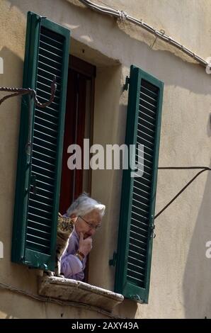 Femme et chat hors fenêtre sur rue à Pienza, Italie. Banque D'Images