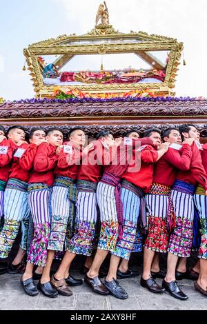 Santiago Atitlan, Guatemala - 19 avril 2019: Les hommes mayas vêtus de vêtements traditionnels portent Le Vendredi Saint défilé flotter dans la ville du lac Atitlan. Banque D'Images