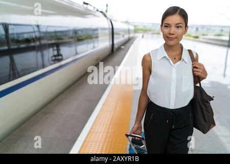 Une femme asiatique qui va faire un voyage d'affaires en train. Voyageur en attente de voyage sur plateforme. Femme d'affaires debout avec des bagages à la gare centrale prête à partir pour les vacances. Banque D'Images