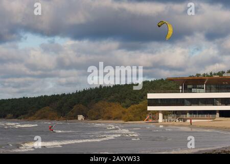Tallinn, Estonie - 18 octobre 2008: Le kitesurfer dans un costume rouge monte sur les vagues de la mer tenant sur une corde tendue d'une voile. Nuageux et venteuse. B Banque D'Images