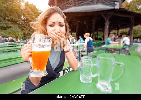 Une fille essaie une bière avec une expression de dégoût dans un bar de rue. Concept d'empoisonnement à l'alcool et de cesser de boire Banque D'Images