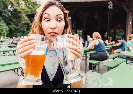 Drôle et folle fille asiatique avec deux Bières sur la terrasse du restaurant de bière en Allemagne. Le concept d'un hanguleur et d'un voyage Oktoberfest Banque D'Images