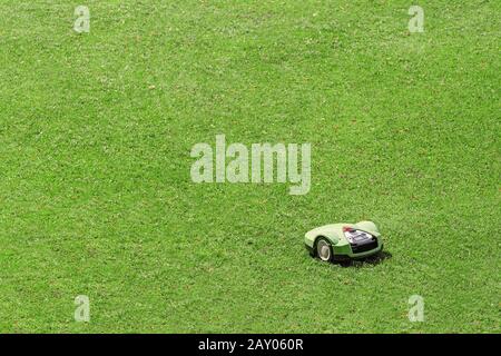 Robot tondeuse fonctionnant sur l'herbe dans la position de stationnement Banque D'Images