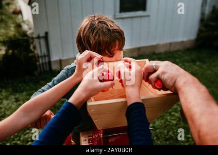 Père et trois enfants dans le jardin pressant des pommes pour faire du cidre, États-Unis Banque D'Images