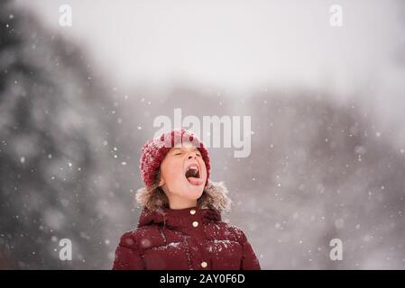 Fille debout dehors prenant de la neige dans sa bouche, Wisconsin, États-Unis Banque D'Images
