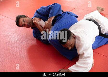 Judokas pratiquant le judo pendant un sparing dans une salle de sport Banque D'Images