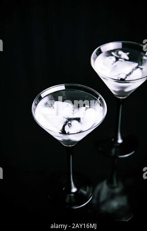 Deux verres à cocktail avec boisson martini avec glace sur fond noir branché. Concept de date du soir ou de la nuit. Banque D'Images