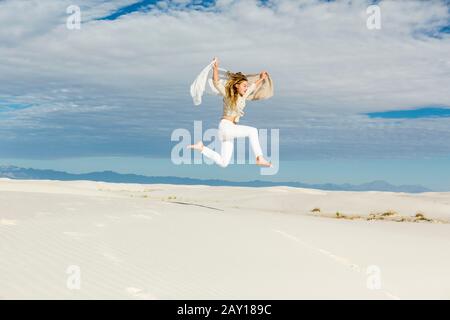 fille de 13 ans dansant et en lésant n mi-air dans l'espace ouvert sur les dunes de sable blanc Banque D'Images
