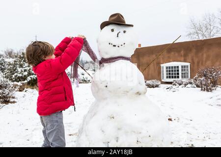 Un garçon de six ans construit un bonhomme de neige Banque D'Images