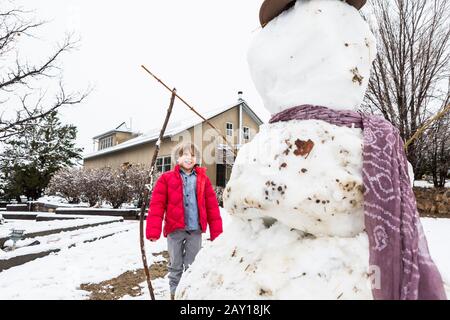 Un garçon de six ans construit un bonhomme de neige Banque D'Images