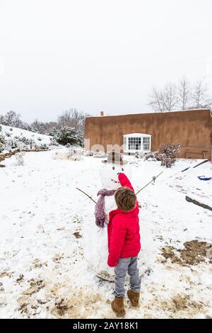 Un garçon de six ans construit un bonhomme de neige Banque D'Images