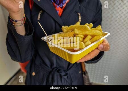 Oosterscheldekering, Pays-Bas, Août 2019. Le plat principal d'un kiosque à cuisine de rue : frites. Une partie est maintenue d'une main pendant le TH Banque D'Images