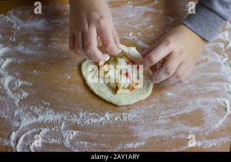 Femme chef mains préparant des tartes pour le dessert pour le thé. Pâte crue avec tranches de pomme pour la cuisson au four. Banque D'Images