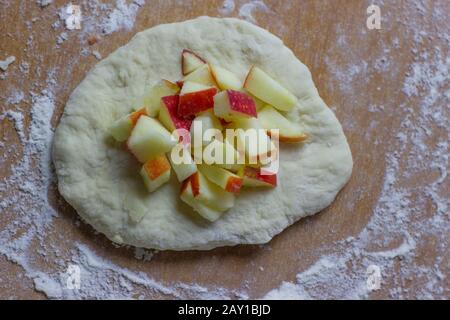 Morceaux de pommes tranchés pour farcir sur une poêle de pâte brute. Banque D'Images