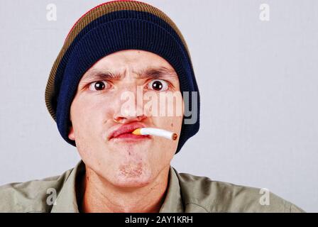 Visage drôle jeune homme avec cigarete dans la main Banque D'Images