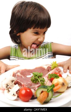 Joli garçon positif et viande et légumes crus dans la lecture de plaques pour la cuisson Banque D'Images