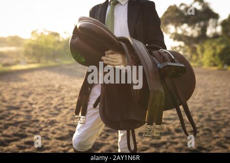 Homme marchant avec une selle de cheval de dressage Banque D'Images