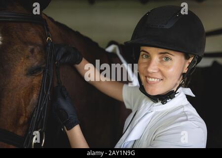 Femme préparant son cheval de dressage dans une écurie Banque D'Images