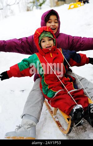 les enfants s'amusent ensemble en descente lors d'une agréable journée d'hiver Banque D'Images