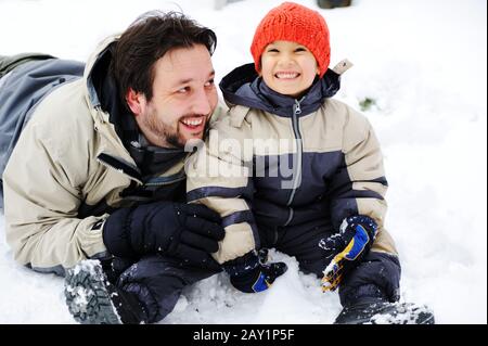 Père et fils jouant avec bonheur dans la neige, saison d'hiver Banque D'Images