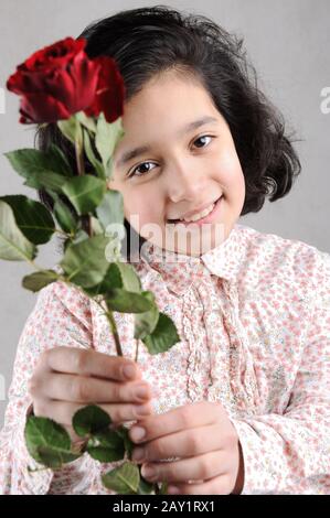 Jolie fille avec une belle rose rouge dans ses mains Banque D'Images