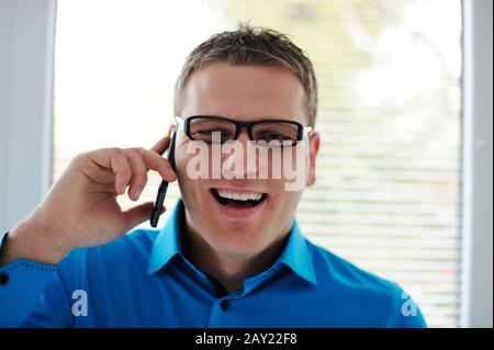 Portrait d'un jeune homme heureux parlant sur un téléphone portable Banque D'Images