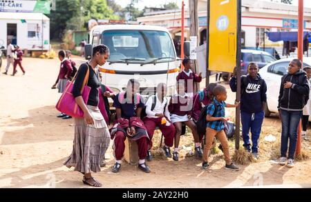 Mbabane, Swaziland, 26 mai - 2019: Lady marchant devant les enfants sur le bord de la route Banque D'Images