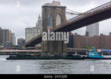 New York, États-Unis - 20 août 2018 : remorqueur poussant une barge chargée de déchets sous le pont de Brooklyn sur la rivière East à New York Banque D'Images