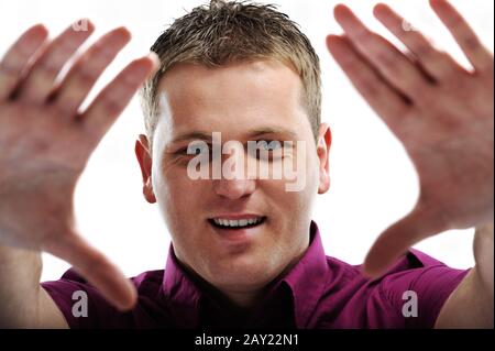 Portrait de l'homme souriant faisant le cadre avec les mains sur fond blanc Banque D'Images