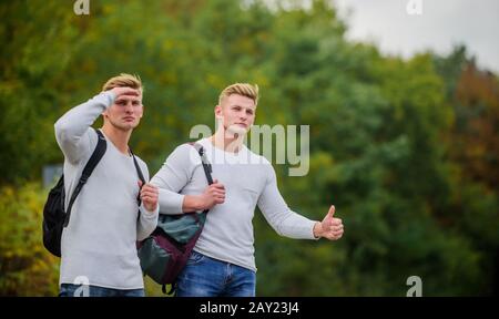 Des amis qui voyagent avec des hitchhikers. Geste de randonnée. Commencez une grande aventure dans votre vie avec la randonnée pédestre. Compagnie amis voyageurs qui déchire à la route nature fond. Voyageurs en route. Banque D'Images