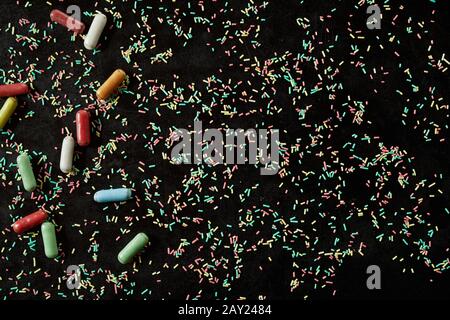 Texture de fond de la cuisson colorée saupoudrer avec une bordure de bonbons à la réglisse enrobée de sucre sur le côté dans une vue plein cadre Banque D'Images