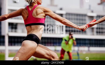 les femmes relatisent l'équipe de passage de la baton dans la compétition d'athlétisme Banque D'Images