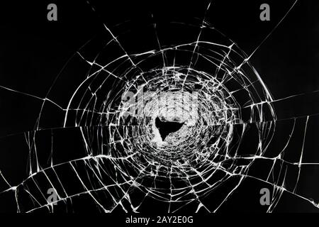 Fissures sur le verre cassé. La fenêtre est endommagée par une balle provenant d'une arme à feu. Pare-brise transparent d'une voiture avec un trou après les coups. Banque D'Images