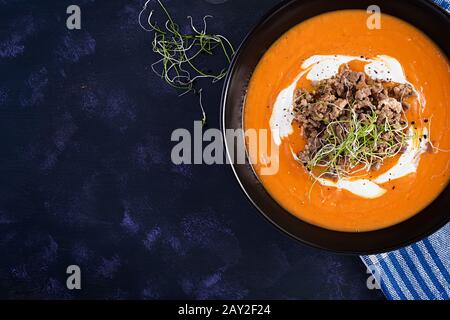Délicieuse soupe de citrouille à la forcemange rôtie faite de viande hachée de boeuf dans un bol sur une table sombre. Jour De Thanksgiving. Vue de dessus, en hauteur Banque D'Images