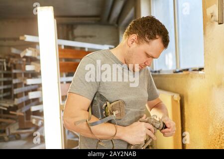 Carpenter comme peintre nettoie la buse de son pistolet dans l'atelier Banque D'Images