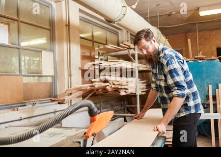 Carpenter travaille avec la scie circulaire dans l'atelier de menuiserie Banque D'Images