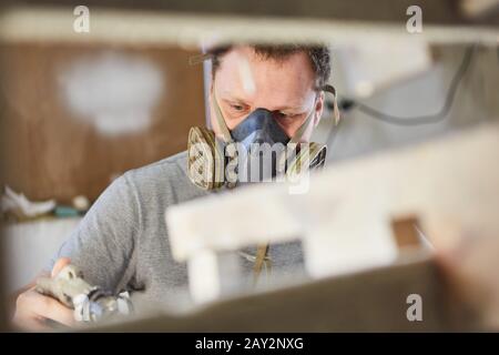 Homme comme peintre avec masque respiratoire coloration ou peinture du bois Banque D'Images