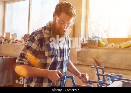 Carpenter avec des lunettes de sécurité travaille sur un étau dans la menuiserie Banque D'Images