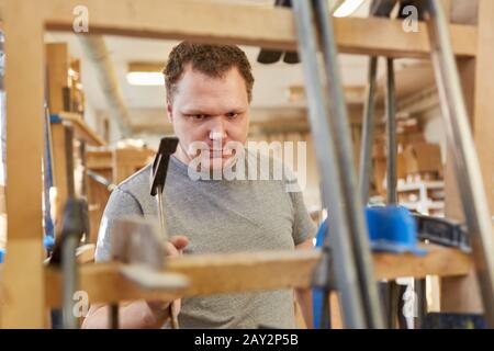 Carpenter apprenti travaille avec des pinces à vis dans la menuiserie de la fabrication de meubles Banque D'Images