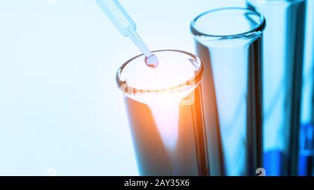 Pipette de gros plan qui dépose un échantillon de solution bleue dans le tube à essai en laboratoire. Concept de resocation scientifique et de biologie de la nanotechnologie. Mise au point sélective Banque D'Images