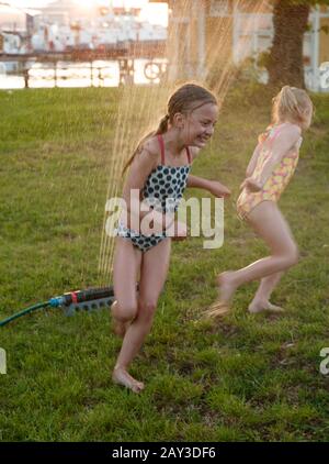 Filles jouant avec arroseur d'eau dans le jardin Banque D'Images