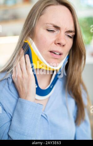 Woman Wearing Neck Brace à la grimace de douleur Banque D'Images