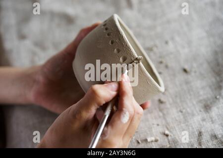 Les mains tiennent un bol pour le moulage des produits en argile Banque D'Images