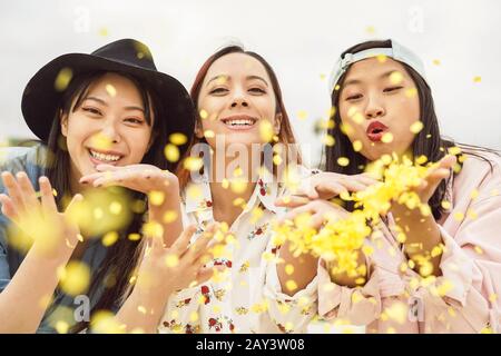 Joyeux amis asiatiques qui s'amusent à lancer des confettis en plein air - jeunes gens branchés célébrant l'événement du festival du carnaval Banque D'Images