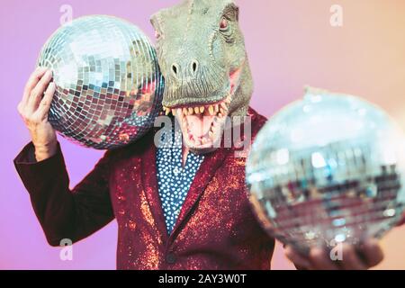 Homme senior ayant du plaisir à porter le masque t-rex dans la discothèque - Élégant homme mascarade dinosaure célébrant la fête du carnaval dans le club de discothèque Banque D'Images